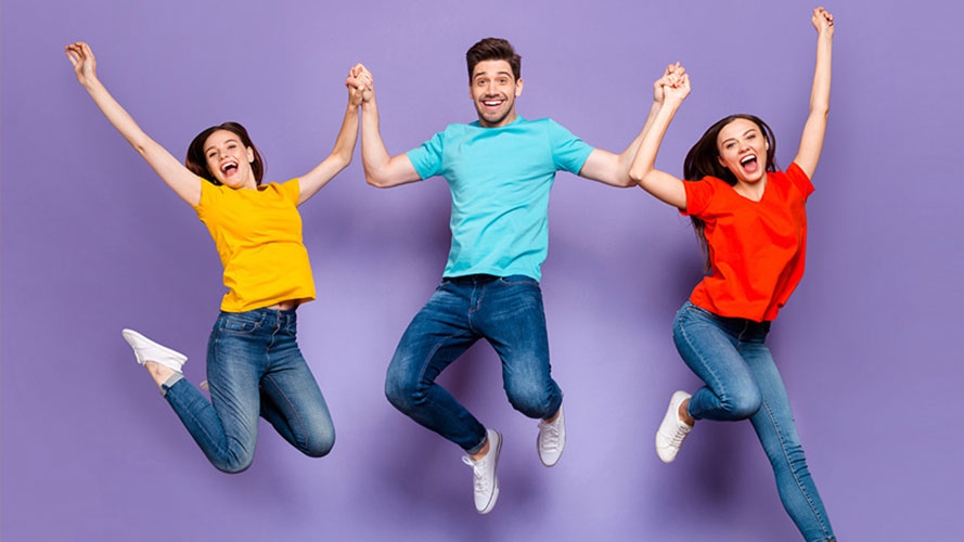 Drei glückliche junge Studenten springen in die Luft, auf violettem Hintergrund